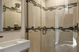 River-pebble shower-pan floor with tan stone-look porcelain tile, master bath