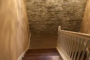 Stained oak hardwood stair treads with stacked-stone wall