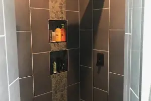 River-pebble shower floor with charcoal large-format tile, walk-in shower