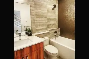 Gray wood-look tile floor with gold glass-mosaic accent wall, bathroom