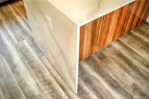Weathered gray wood-look plank floor with quartz waterfall panel